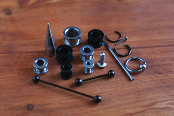 Set voor piercing piercing accessoires op houten achtergrond. een katheter voor de tong een staaf in de tong en wenkbrauw, oorbellen    - Foto, afbeelding