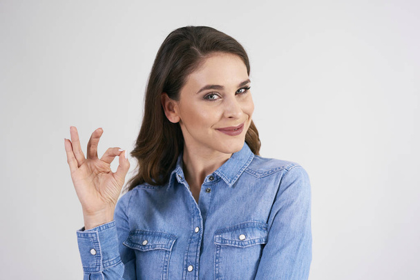 Smiling woman showing ok sign in studio shot  - Photo, Image
