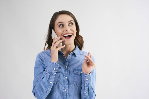 Boldog, fiatal nő használ mozgatható telefon-ban Műterem szemcsésedik  - Fotó, kép