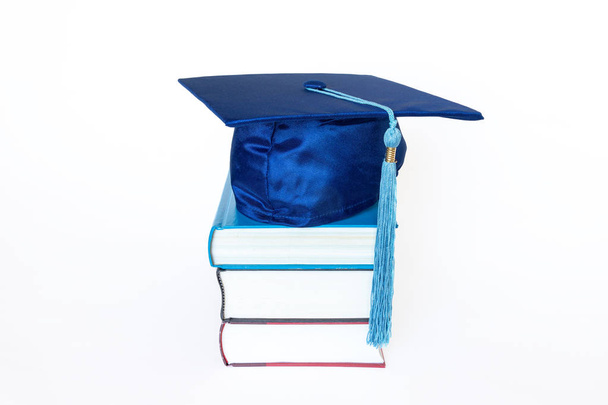 Tapa de graduación con borla en libros aislados sobre fondo blanco
 - Foto, imagen