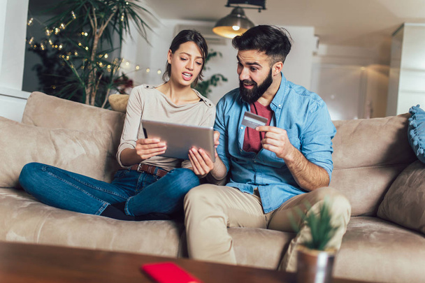 Улыбающаяся пара с помощью цифрового планшета и кредитной карты дома
 - Фото, изображение