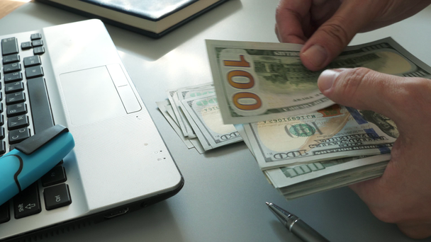 Mies työpöydällä laskemassa rahaa ja pino dollarin seteleitä
. - Materiaali, video