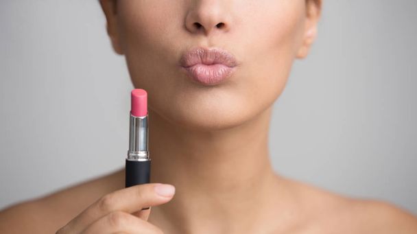 Lady Holding roze lippenstift en het verzenden van Air Kiss - Foto, afbeelding