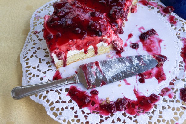 Pół jedzone ciasto z kremem i czerwonymi jagodami - Zdjęcie, obraz