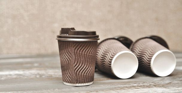 Brązowe kubki papierowe do kawy na drewnianym tle. - Zdjęcie, obraz