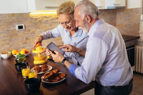 Aged couple busy look at digital tablet while having delicious b - Foto, Bild