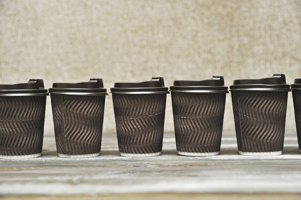 Tasses en papier marron pour café sur fond en bois
. - Photo, image