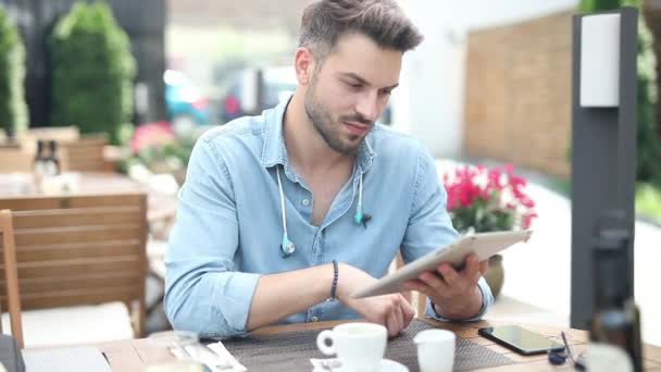 Happy casual man zit in restaurant en leest goed nieuws op zijn Tablet pad computer en viert rustig met hand gebaar - Video