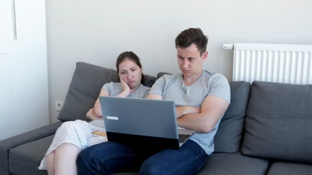 Znudzony śpiący Para mężczyzna i kobieta oglądają wideo na laptopie siedzi na kanapie. - Materiał filmowy, wideo
