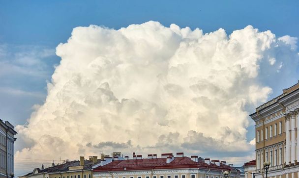 grote witte wolk over daken van huizen - Foto, afbeelding
