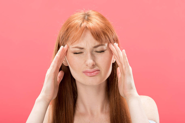 front view of redhead young woman with headache touching head isolated on pink - Photo, Image