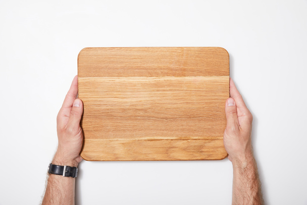 top view of man holding wooden chopping board on white background - Foto, Bild