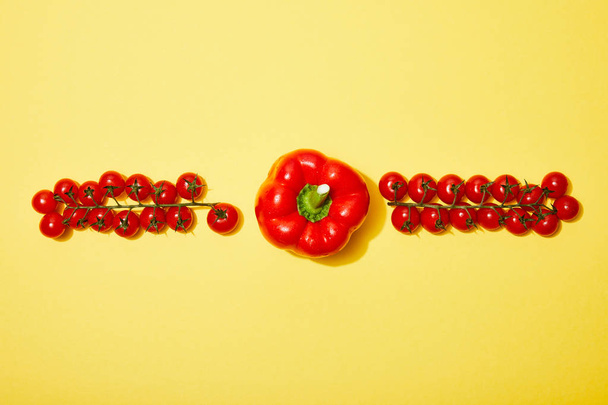 flat lay with red cherry tomatoes and paprika on yellow background - Fotó, kép