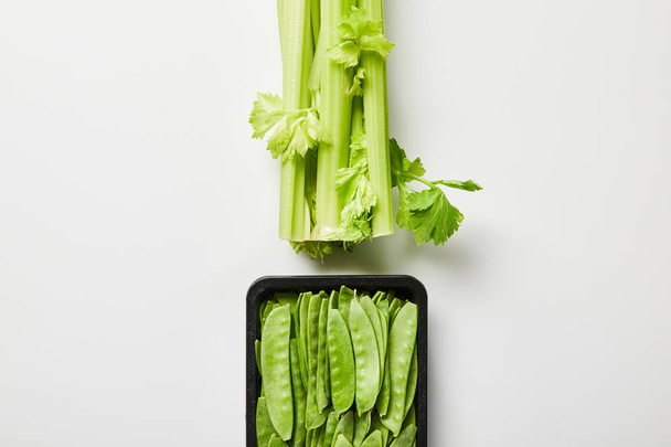 top view of green organic leek and peas in box on white background - Фото, зображення