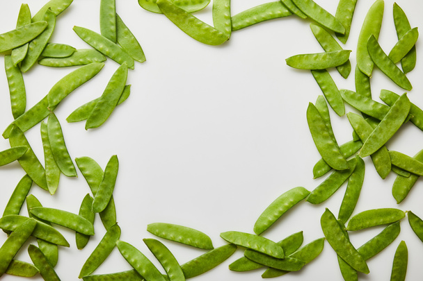 marco de guisantes verdes esparcidos sobre fondo blanco
 - Foto, Imagen