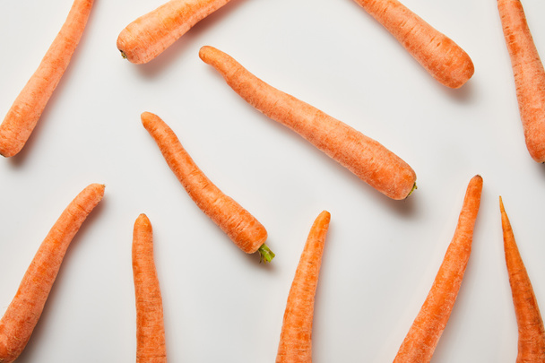 top view of fresh carrots scattered on white background - Valokuva, kuva