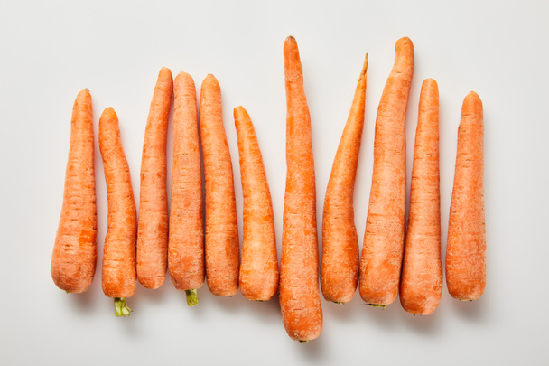 vista superior de zanahorias frescas en fila sobre fondo blanco
 - Foto, Imagen