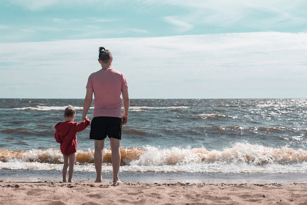 Dad and son hold hands and look at the sea. Friendship and love between child and parent - Fotoğraf, Görsel