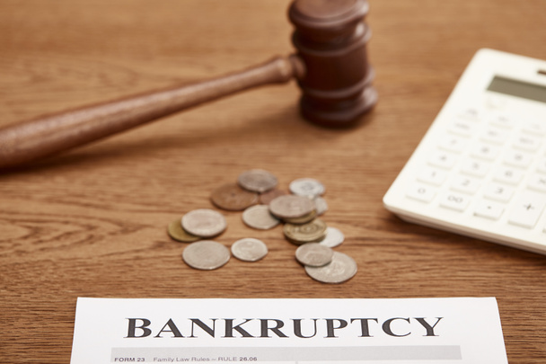 selective focus of bankruptcy form, gavel, calculator and coins on brown wooden table - Photo, Image