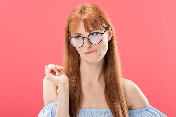 pensive redhead girl in glasses looking away isolated on pink - Фото, изображение