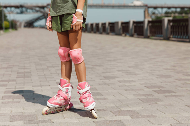 Teenage girl in a helmet learns to ride on roller skates outdoors - Foto, Bild