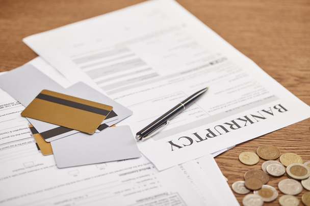 bankruptcy form among documents, credit cards and coins on wooden table - Photo, Image