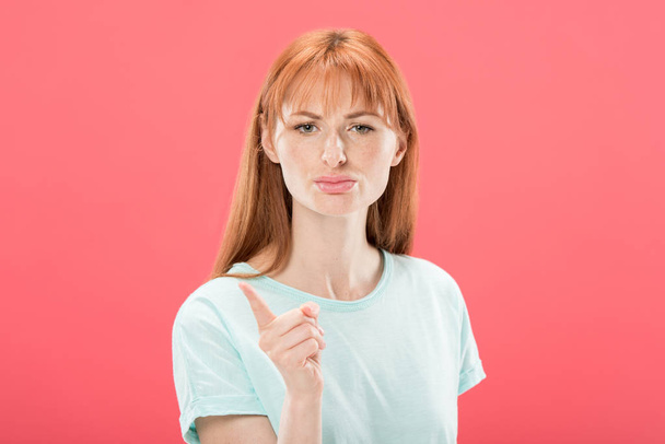 front view of displeased redhead girl in t-shirt looking at camera and shaking finger isolated on pink - Фото, изображение