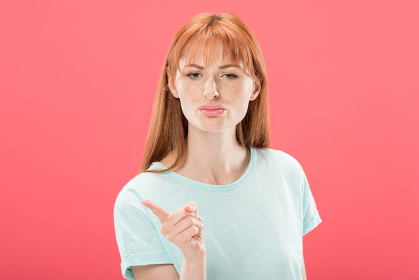 front view of displeased redhead girl in t-shirt looking at camera and shaking finger isolated on pink - Zdjęcie, obraz