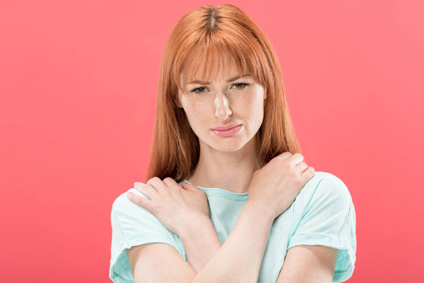 front view of upset redhead girl in t-shirt looking at camera isolated on pink - Foto, immagini