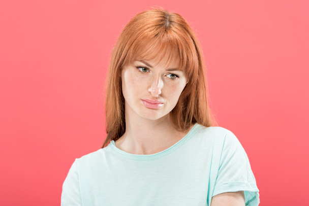 sad pensive redhead girl in t-shirt looking away isolated on pink - Foto, afbeelding