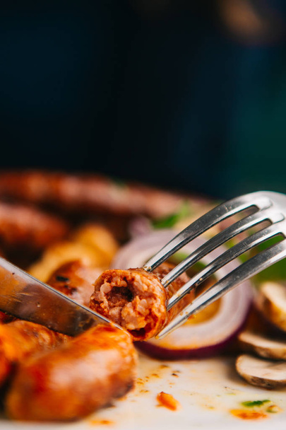 close-up view of fork, knife and sausages on plate - Foto, Imagem