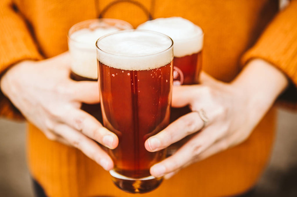 close-up partial view of person holding three glasses full of cold beer - Photo, image
