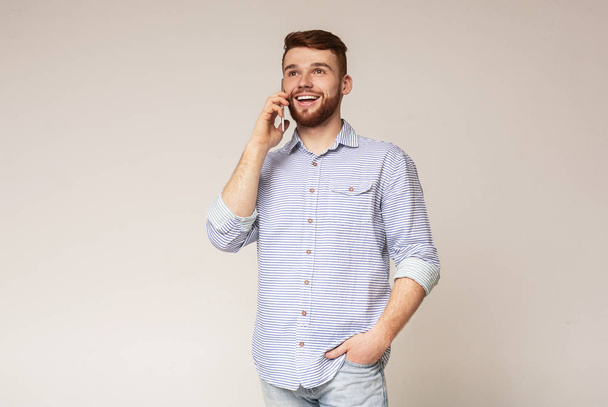 Веселый человек, пользующийся телефоном и широко улыбающийся
 - Фото, изображение