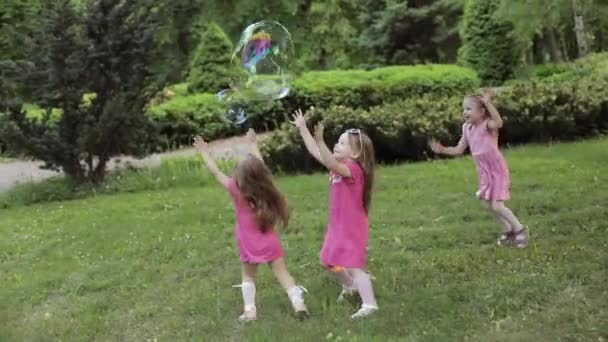 Szczęśliwe dziewczynki bawią się w ogrodzie i bawią się bąbelkami - Materiał filmowy, wideo