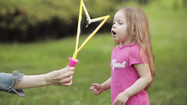 Confident playful little cute girl blowing huge air soap bubble blower medium close-up - Footage, Video