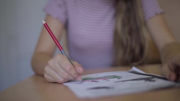 Happy schoolgirl sitting at desk and writing in exercise book - Materiaali, video