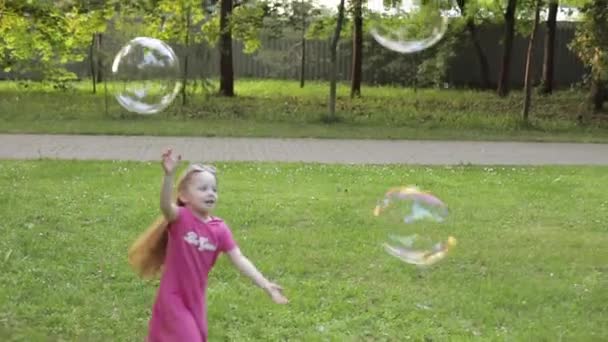 大きなエアソープバブルブロワーをキャッチしようとして遊ぶ幸せな小さな子供の女の子のグループ - 映像、動画
