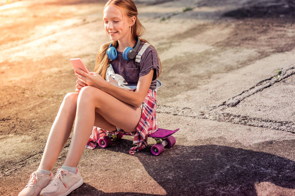 Joyful good-looking little girl in summer outfit wearing sneakers - Fotó, kép