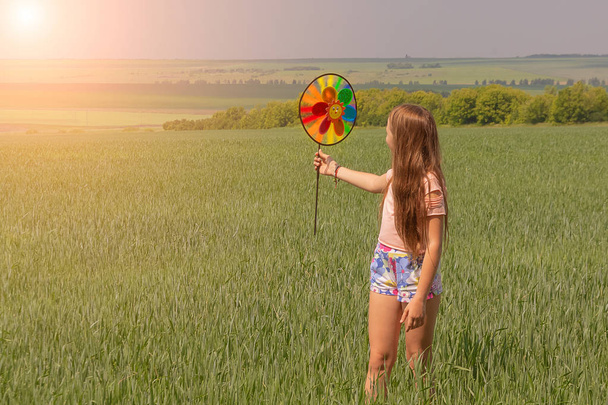 Onnellinen tyttö pitkät hiukset on tilalla värillinen tuulimylly lelu käsissään
. - Valokuva, kuva