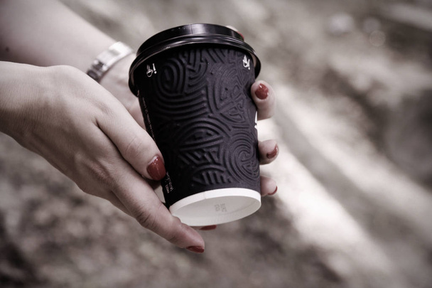 Mano femminile con tazza di carta nera di caffè da asporto
 - Foto, immagini