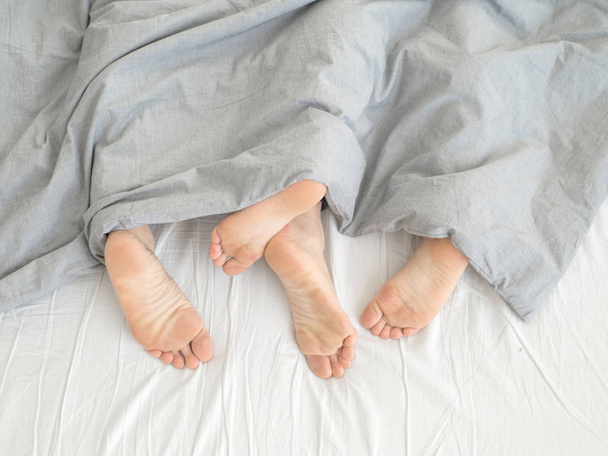 Ноги пары бок о бок в постели
 - Фото, изображение