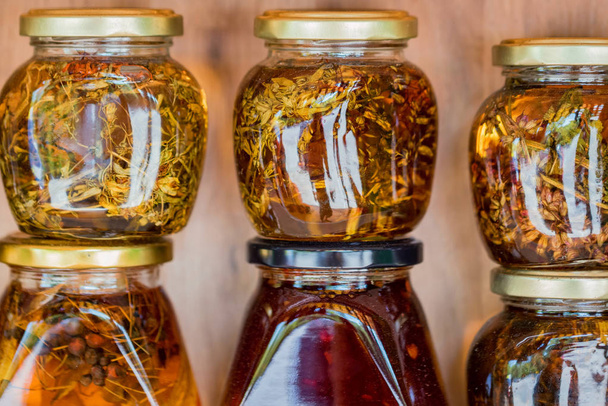 Frascos con miel y hierbas naturales de colores para la venta en estantes
 - Foto, Imagen