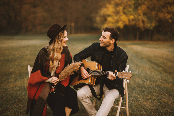 Preciosa pareja teniendo una cita en el parque y tocando en la guitarra
 - Foto, imagen