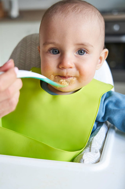 Portrait Of Smiling Baby Boy At Home In High Chair Being Fed Sol - Foto, imagen