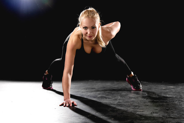 Sports girl performs pushups from the floor on one hand. - Foto, imagen