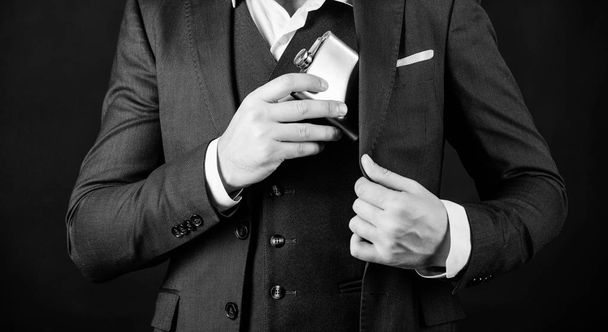 Guy hide metal flask into pocket. Alcohol drink concept. Have alcohol drink with you. Always with me. Flat metal bottle for alcohol. Man bearded hipster wear elegant suit hold metal flask for alcohol - Photo, image