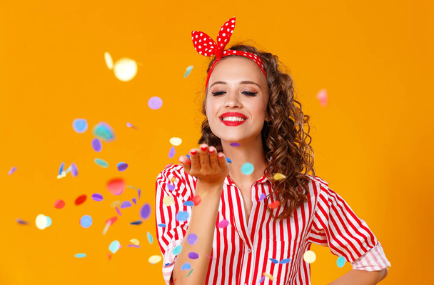 веселая юная женщина с праздничными конфетти на желтом
 - Фото, изображение