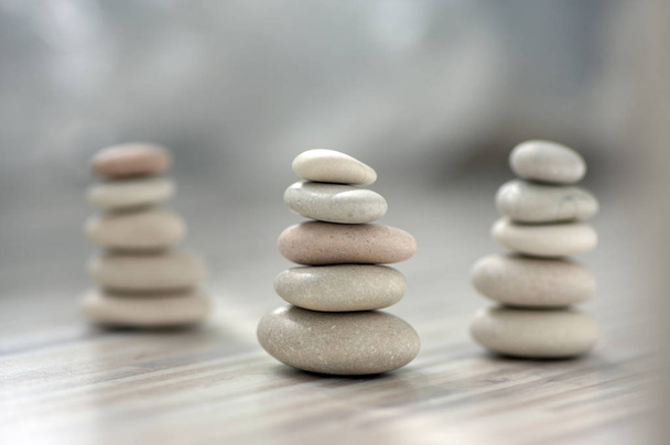 Harmonia e equilíbrio, três cairns, seixos simples poise sobre luz de madeira fundo cinza branco, simplicidade escultura zen rocha
 - Foto, Imagem