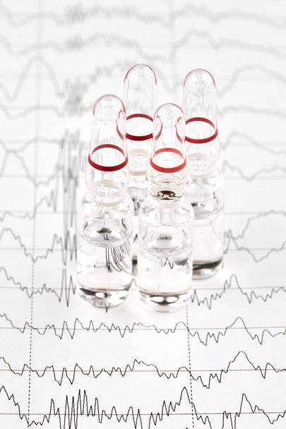 Közeli fotó ampullák a gyógyszert az EKG grafikon - Fotó, kép
