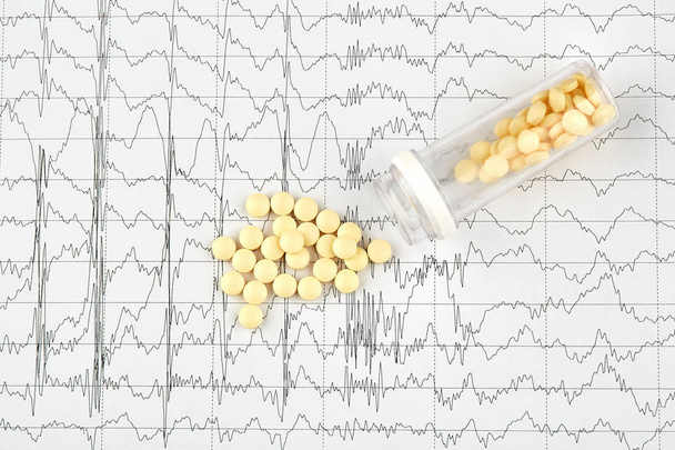 Close-up photo of yellow pills and vial on EKG graph - Photo, Image